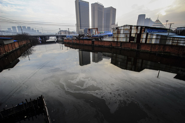 A river polluted by waste oil glimmers in Shaoxing, Zhejiang province, in March. (Photo by Li Ruichang/China Daily)