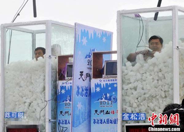 Jin Songhao (R) sits in a box of ice cubes during a contest at Jiamusi, Northeast China's Heilongjiang province, Sept 13, 2015. (Photo/Chinanews.com)