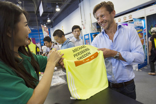 Michael Persberg, a marathon runner from Sweden, has his running vest personalized with his name and country at the Beijing Marathon Expo on Friday. (Photo source:China daily)