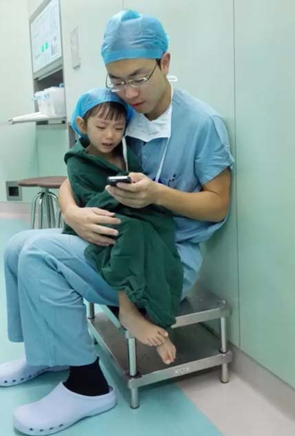 Dr. Shi Zhuo comforts a little toddler patient with a cartoon app on his cell phone before heart surgery in Hangzhou, Zhejiang province, Sept 18, 2015. (Photo/weibo.com)