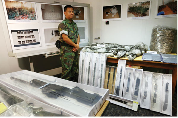 A police officer displays weapons and other contraband goods during a news conference on operation Thunderbolt 15 on Wednesday. (Photo by Roy Liu / China Daily)