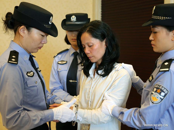 Kuang Wanfang (2nd R), an economic crime suspect, is handcuffed after arriving at the Changle Airport in Fuzhou, southeast China's Fujian Province, Sept. 24, 2015. The woman, who fled to the U.S. in 2001, is suspected of taking part in corruption and bribery, and was repatriated to China on Thursday thanks to close cooperation between Chinese authorities and their U.S. counterparts. The move followed the forced repatriation of Yang Jinjun, one of China's most wanted economic fugitives, from the U.S. on September 18. (Photo: Xinhua/Yin Gang)