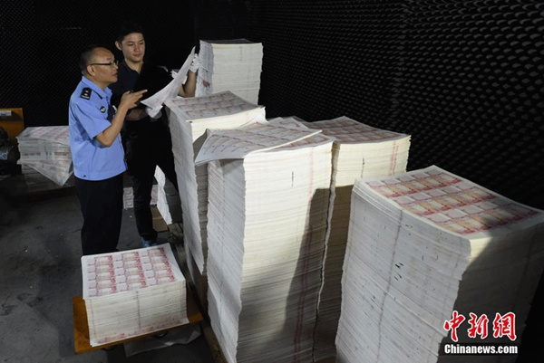 Police officers in Huizhou in South China's Guangdong province examine the paper used for counterfeiting 100-yuan banknotes on September 24, 2015. (Photo/chinanews.com)