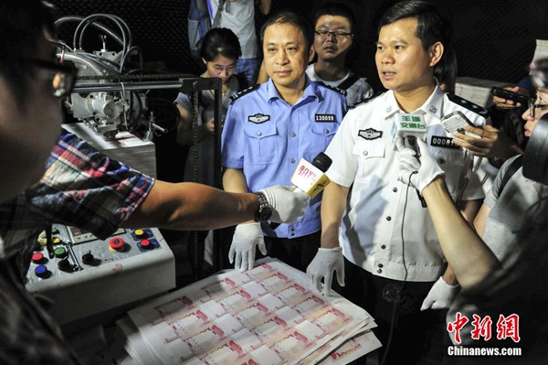 Journalists interview the police officers in a factory that made counterfeit banknotes in Huizhou, in South China's Guangzhou province, on Sept 24, 2015. (Photo/chinanews.com)