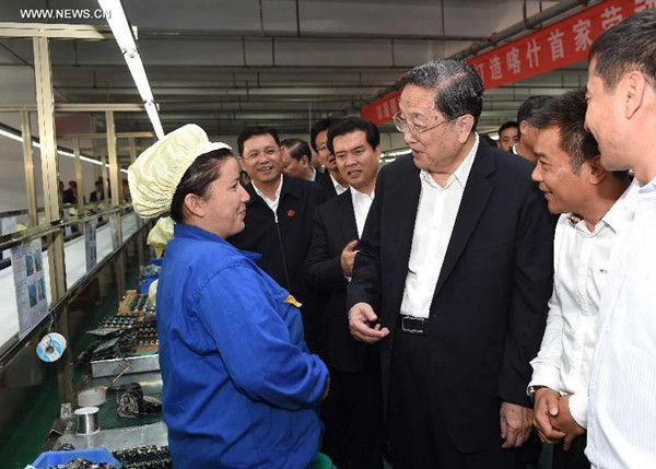 Yu Zhengsheng, chairman of the National Committee of the Chinese People's Political Consultative Conference (CPPCC), talks with workers at production lines of electronic products in the economic development zone in Kashgar, northwest China's Xinjiang Uygur Autonomous Region, Sept. 26, 2015. (Photo: Xinhua/Rao Aimin)