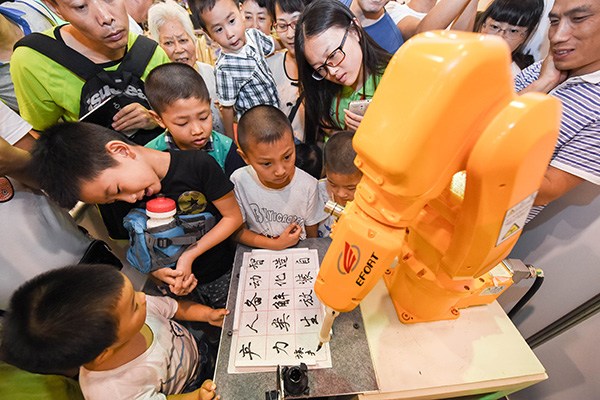 A robot developed by a local company in Anhui province demonstrates calligraphy at an international competition for robots in Hefei, capital of Anhui province. (Photo/China Daily)