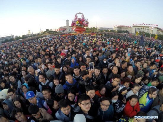 People gather to watch a national flag-raising ceremony marking the 66th anniversary of the founding of the People's Republic of China on the National Day at the Tiananmen Square in Beijing, capital of China, Oct. 1, 2015. (Xinhua/Xing Guangli)