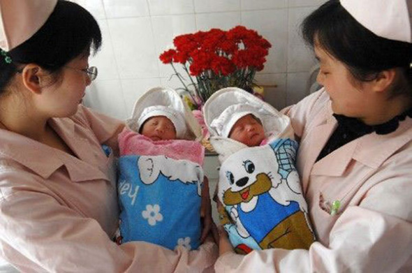 Two nurses hold baby boy and girl twins at a hospital in Hefei, Central Chinas Anhui province. (Photo/Xinhua)