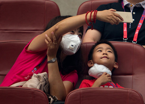 A mother and son pose for a selfie on Wednesday during a break in the China Open tennis tournament in Beijing, where smog has persisted for days.(Photo: China Daily/Wei Xiaohao)