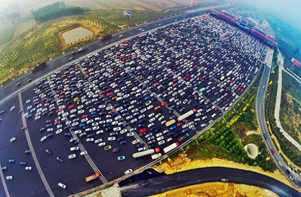 Long lines of vehicles slow traffic at the toll gate of the Beijing-Tianjin-Macao Expressway on Tuesday. Congestion occurred at the site again on Wednesday as holiday travelers headed home.(Photo: China Daily/Fu Ding)