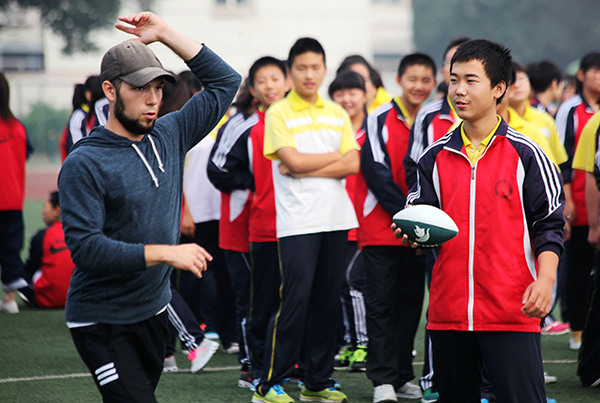 A student from Michigan University in the United States shares the basic steps in playing American football with middle school students in Zhangjiakou, Hebei province. (Photo/China Daily)