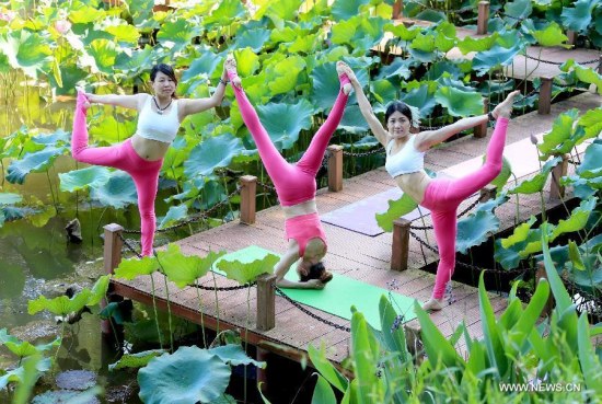Yoga lovers practice yoga beside a lotus pool in Jilingshan Park in Huangshan City, east China's Anhui Province, July 12, 2015. (Photo: Xinhua/Shi Guangde)