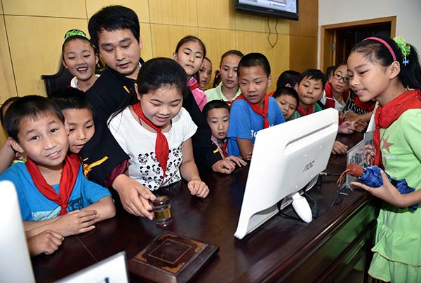 A judge helps a primary school student to use a gavel at an open day event at the No 1 People's Court in Fengjie county, Chongqing, in May. RAO GUOJUN/CHINA DAILY