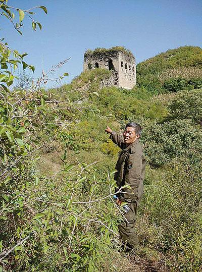 One protector of the Great Wall in Funing county, Qinghuangdao city, Heibei province, points to a damaged section of the historical structure. (Photo/China Youth News)