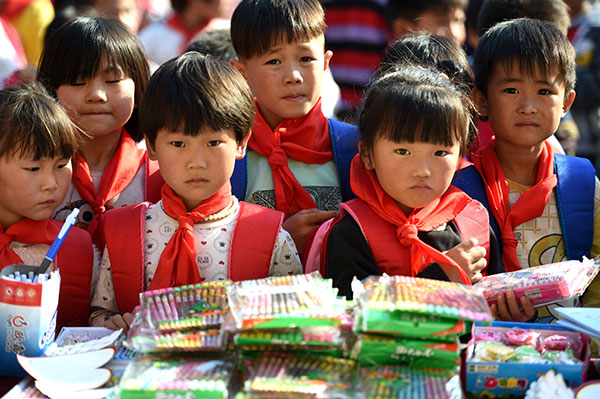 Children from poor families in Bozhou, Anhui province, receive stationery donated by volunteers. China will work hard to lift about 70 million people in rural areas out of poverty by the end of 2020. (Photo: China Daily/ Liu Qinli)