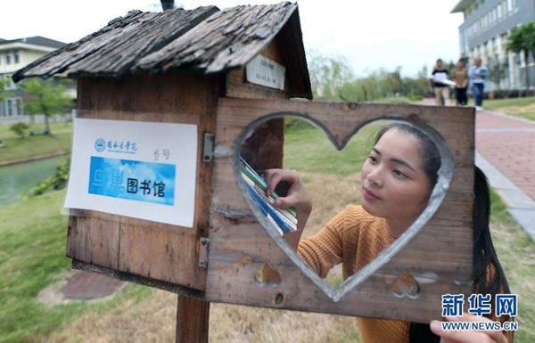 Photo taken on Oct 13, 2015 shows a student borrowing books from a self-service book box in the shape of a birdhouse on the campus of Guilin Medical University in South China's Guangxi Zhuang autonomous region. (Photo/Xinhua)