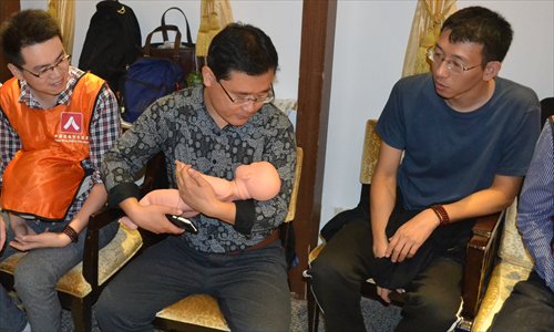 A man learns how to cuddle a baby at the men's morals class in Beijing. (Photo/Courtesy of Fang Gang)