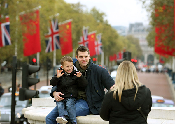 Tourists pose for a photograph in The Mall near Buckingham Palace on Monday. President Xi Jinping is scheduled to officially start his trip to the United Kingdom on Tuesday. WU ZHIYI/CHINA DAILY