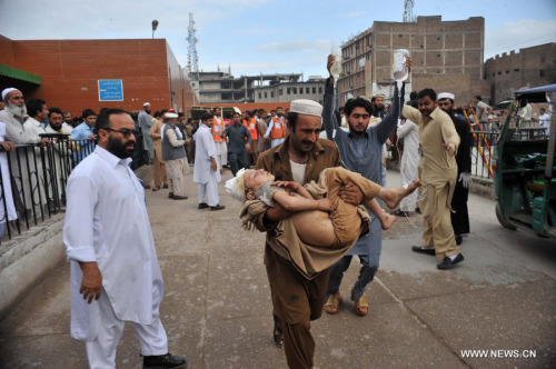 A man holds a boy injured in an earthquake at a hospital in northwest Pakistan's Peshawar, on Oct. 26, 2015. The Pakistani government and army has kicked off a rescue and relief operation in the areas where an earthquake measuring 8.1 on the Richter Scale played havoc, reportedly killing over 220 people and injuring 1,200 others on Monday, officials said. (Photo: Xinhua/Umar Qayum)