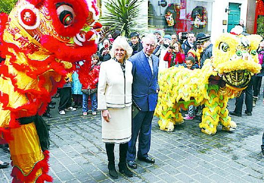 Britain's Prince Charles and his wife, Camilla, Duchess of Cornwall, are greeted by two Chinese lions as they visit China Town in London, February 19, 2015. (Photo/Dazhong Daily)