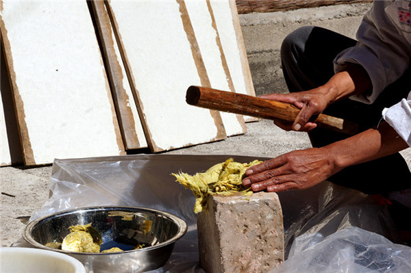 After boiling, He mashes the bark with a stick until it becomes paper pulp. (Photo by Xu Jing/chinadaily.com.cn) After boiling, He mashes the bark with a stick until it becomes paper pulp. (Photo by Xu Jing/chinadaily.com.cn)