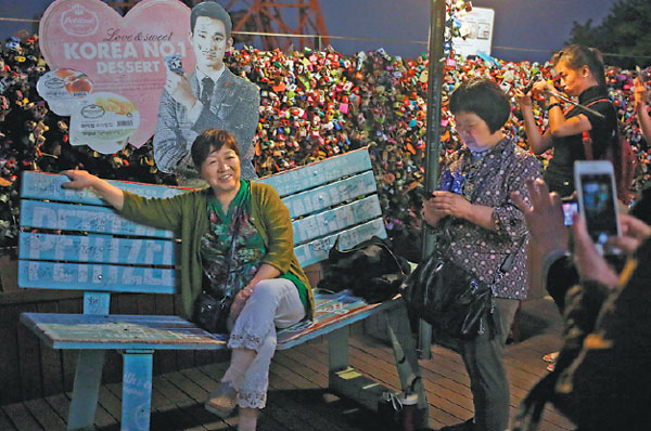 Chinese tourists take photos near the Seoul Tower in Seoul in April. The city hosted a series of events in tourist destinations in May to attract visitors from China. Liu Zhe / China Daily