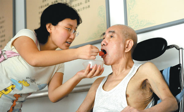 A volunteer takes care of a patient at the hospice ward in the Beijing Chaoyang Hospital. Wang Yixuan / For China Daily