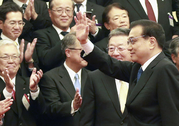 Premier Li Keqiang waves to delegates from the Japan-China Economic Association after a group photo at the Great Hall of the People in Beijing on Wednesday. FENG YONGBIN/CHINA DAILY