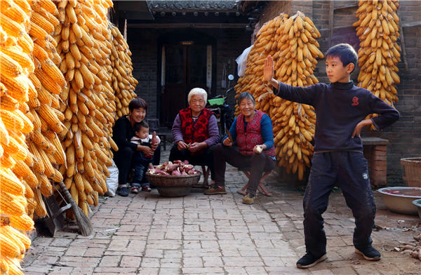 A boy practices tai chi at his home in Chenjiagou on Nov 1, with newly harvested corn hanging nearby. Xu Hongxing / for China Daily