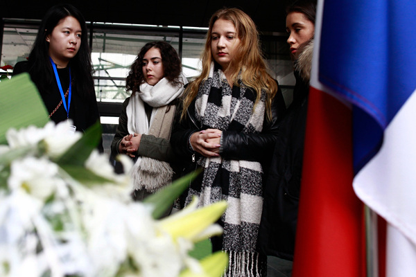 People in Beijing gathered at the French embassy in China on Sunday to mourn the victims of the Paris attack. The embassy lowered the tricolor flag to half-staff. (Photo by Zhu Xingxin/China Daily)