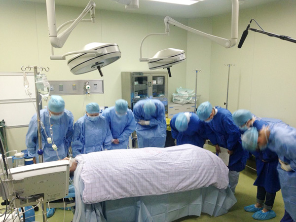 Doctors and nurses pay tribute to Jiao Yu's remains before the operation to remove his organs at Fudan University's Huashan Hospital in Shanghai, Nov 2, 2015. (Photo/huashan.org.cn)