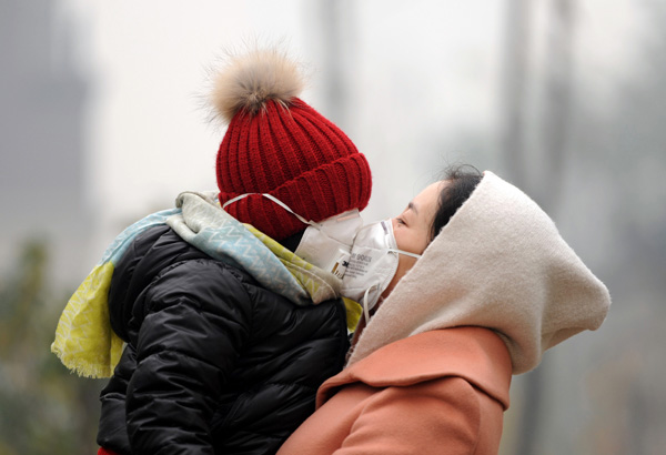 A mother and her daughter protect themselves from the heavy smog in Shenyang, Liaoning province, on Sunday. (Photo/China Daily)