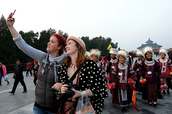 Two foreign tourists take pictures in Beijing's Temple of Heaven. Despite an increase in the number of overseas visits in the first nine months of this year, the inbound tourism industry is unlikely to meet its five-year target. (Photo/China Daily)