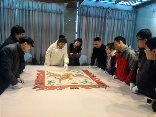 Artist and scholar Sun Ping (center) shows visitors a relic of a Peking Opera performance at the Imperial Court Opera Institute of the Palace Museum in Beijing. (Photo provided to China Daily)