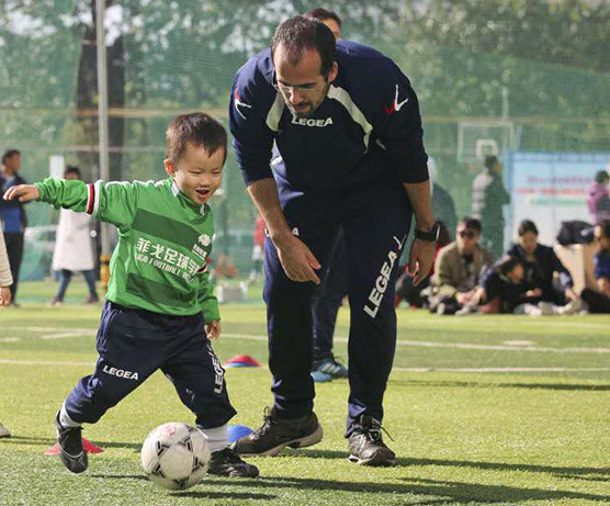 A Portuguese soccer coach teaches a young boy how to dribble at the WinningLeague Luis Figo Soccer Academy in Beijing. (Photo provided to China Daily)