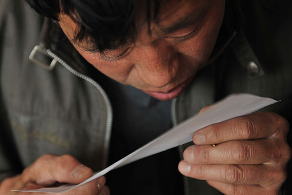 Wu Zhicheng, a Beijing resident who has no hukou, checks a paper that may help him reinstate his household registration in January. Wu said he lost his hukou 43 years ago because of a mistake that occurred when the local police relocated it to his employer. Wu Jiang / for China Daily