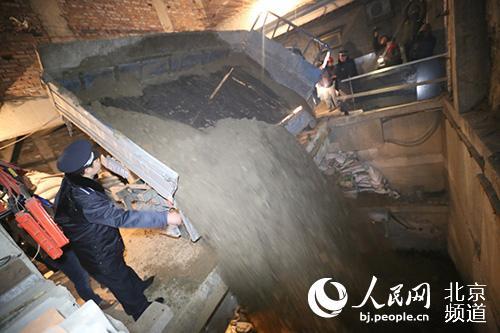 Law enforcement officers with the Urban Management Bureau of Dongcheng District direct workers to backfill a huge basement in Beijing on Nov. 26, 2015. (Photo/Bj.people.cn)