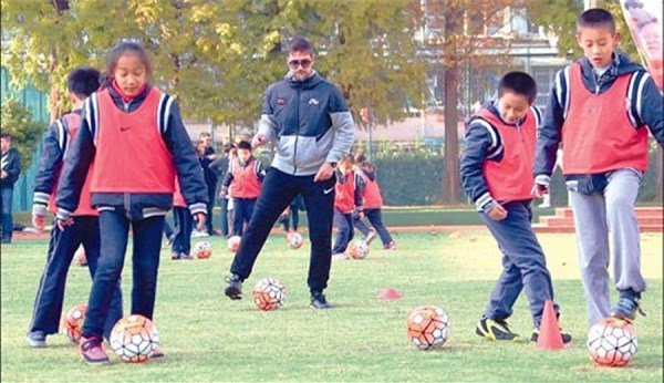 Jefrey Callau Casanova (center) puts a group of schoolchildren through their paces in a soccer lesson yesterday at the Affiliated Primary School of the University of Shanghai for Science and Technology.(Wang Rongjiang)
