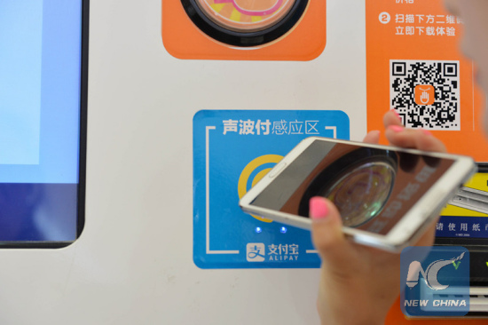 A visitor experiences the sound wave payment function of mobile phone during the Mobile World Congress Shanghai in Shanghai, east China, July 17, 2015.(Xinhua/Liu Xiaojing)