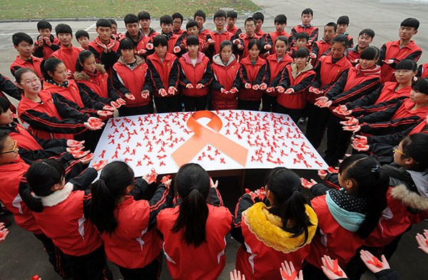 Students display a panel of red ribbons calling for HIV/AIDS prevention at Shahe No 1 Middle School in Hebei province on Sunday. (CHEN LEI/XINHUA)