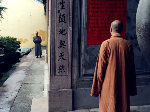 A monk is learning Buddhism while another reading a notice. (Photo: chinadaily.com.cn/Ruan Fan)