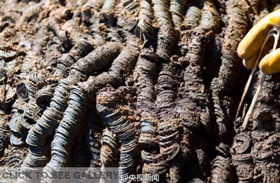 An archaeologist shows ancient coins unearthed at a royal tomb in East China's Jiangxi province. Archaeologists uncovered a total of two million copper wuzhu coins from the imperial tomb for the Marquis of Haihun State near present-day Nanchang. (Photo/Weibo account of CNTV)