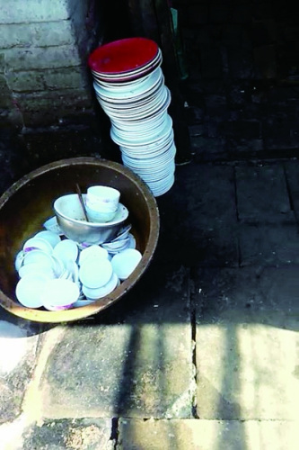 Bowls and dishes placed outdoors at the rice and chicken restaurant. (Photo/The Mirror)