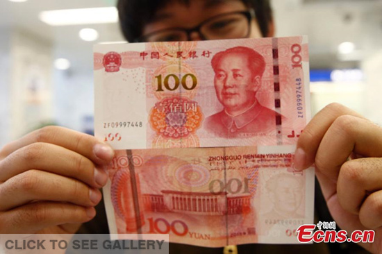 A resident shows new 100-yuan bank notes in a branch of the Bank of Communications in Beijing on November 12, 2015. The new 100-yuan bank note is put into use from Thursday, November 12. (Photo: China News service/ Zhang Hao)