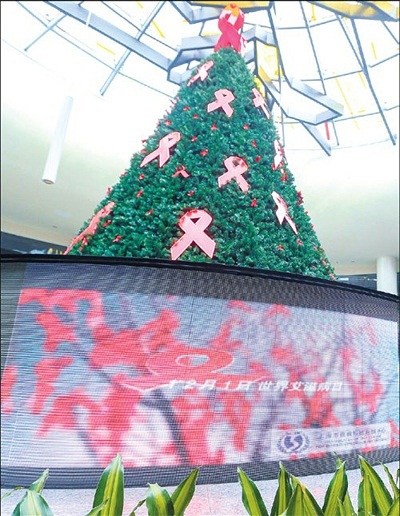 A Christmas tree decorated with red ribbons, the international symbol of the fight against AIDS, is unveiled at the Peoples Square Metro station yesterday to mark World AIDS Day.(Photo/Xinhua)