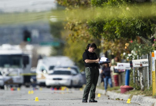 An FBI agent searches the spot where Wednesday's police shootout with suspects happened in San Bernardino, California, Dec. 3, 2015. The two suspects in Wednesday's mass shooting at San Bernardino City of Southern California were heavily armed, police said on Thursday. (Xinhua/Yang Lei)
