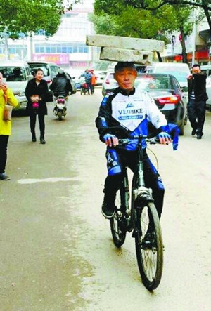 Zhang Xunmu rides a bicycle with a 34 kg millstone and a 15 kg stone block on his head. (Photo/Wuhan Evening News)