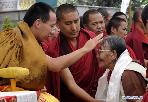 The file photo taken on Aug. 6, 2012 shows the 11th Panchen Lama, Bainqen Erdini Qoigyijabu, offering head-touching blessings to a Buddhist believer in Xigaze, southwest China's Tibet Autonomous Region.  (Xinhua/Chogo)