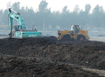 Piles of sewage sludge dumped in the dry bed of the Yongding River in the Daxing district of Beijing, in September. The Beijing Drainage Group said it has taken measures to neutralize the rank odor. Lu Shuchan / for China Daily