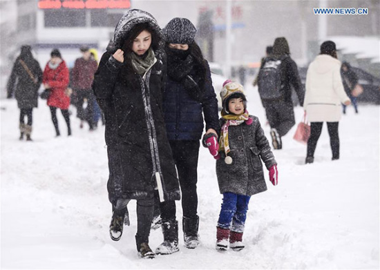 Residents walk on a snowy road in Urumqi, capital of Northwest China's Xinjiang Uygur autonomous region, Dec 11, 2015. A snowstorm hit Urumqi on Dec 11 and the local meteorological bureau has issued a red alert for snowfall. (Photo/Xinhua)